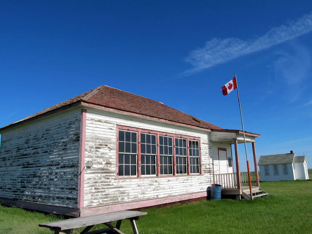 Old schoolhouse with Canadian flag and church on the prairie, 2013