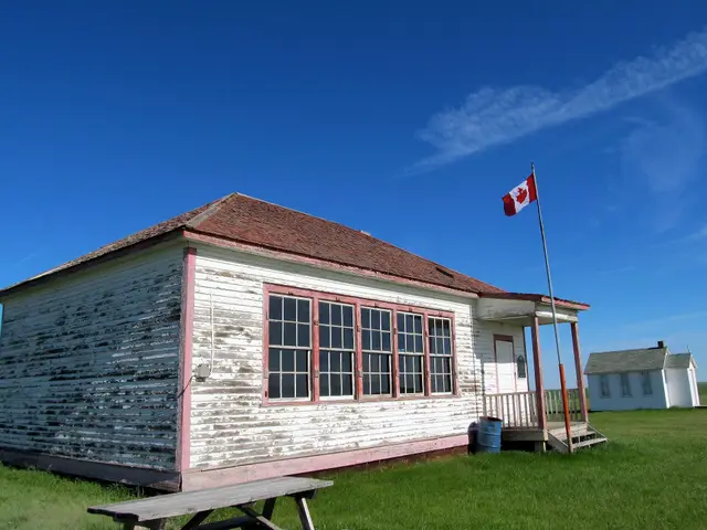 Old schoolhouse with Canadian flag and church on the prairie